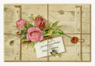 Pink roses and foliage sit atop a wooden panel or crate. A note with holiday wishes is attached…