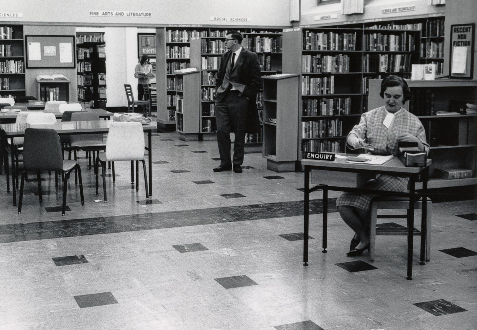 Picture of interior of library with staff at enquiry desk. 