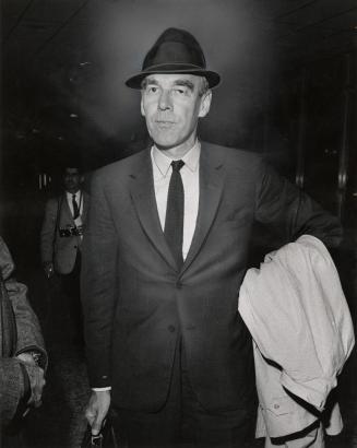 Portrait of older white man in suit and hat carrying briefcase