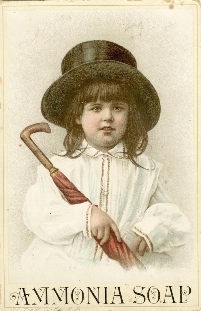 A young girl in a white dress and a black top hat is clutching a closed red umbrella