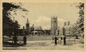 Black and white photograph of an open gate in an iron rail fence. In the background are large,  ...