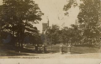 Black and white photograph of an open gate in an iron rail fence. In the background are large,  ...