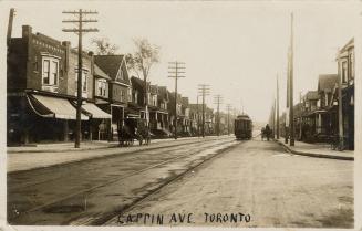 Black and white photograph of a streetcar running a long a track in a mixed neighborhood.