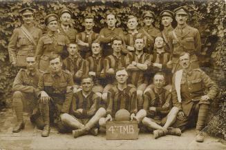 Black and white photograph of a group of men in military uniforms and athletic gear posing in a ...