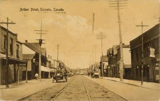 Sepia toned photograph of a city street with buildings on each side of it, automobile in the mi ...