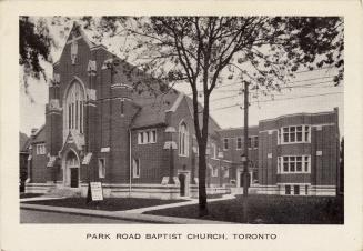 Black and white photograph of a large brick, gothic style church.